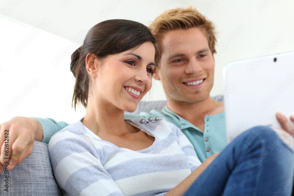 Couple in sofa websurfing on internet with tablet