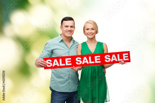 smiling couple with sale sign
