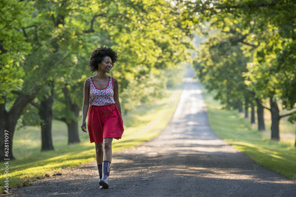 A woman walking down a tree lined path. A woman walking down a tree lined path.