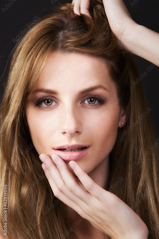 Fototapeta premium Young woman with long hair on dark background