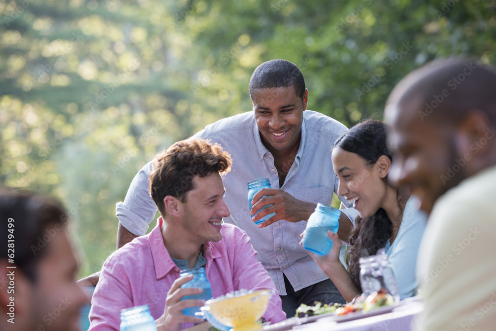 A group of people having a meal outdoors, a picnic. Men and women. A group of people having a meal outdoors, a picnic. Men and women.