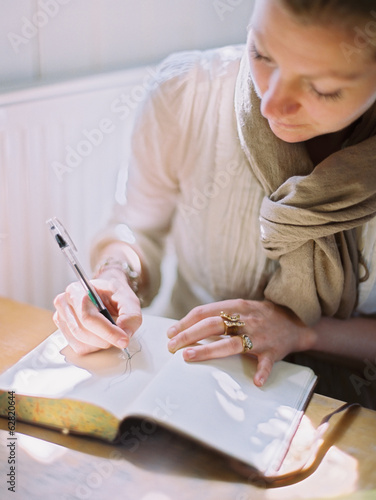 A woman using a coloured pen drawing on a blank page of a diary. photo