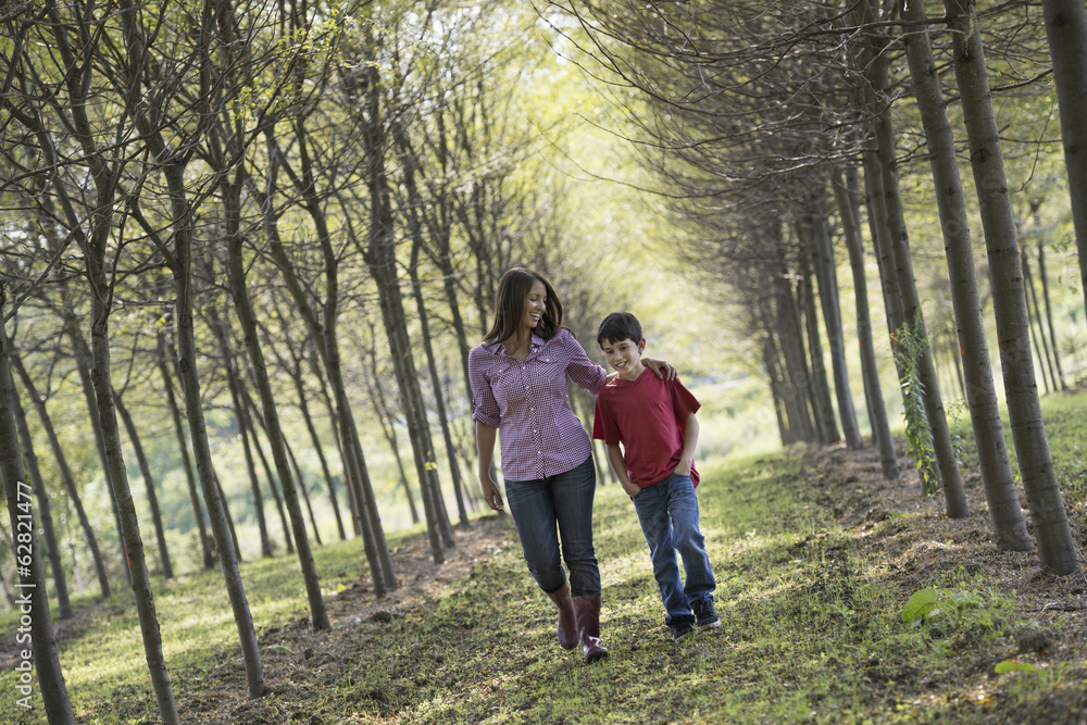 A woman and a child walking down an avenue of trees. A woman and a child walking down an avenue of trees.