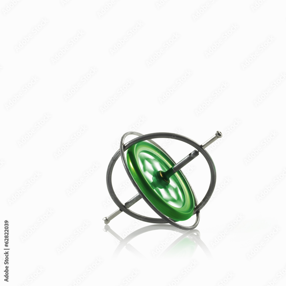 Small metallic object, a gyroscope or spinning wheel with a green patterned centre. Small metallic object, a gyroscope or spinning wheel with a green patterned centre.