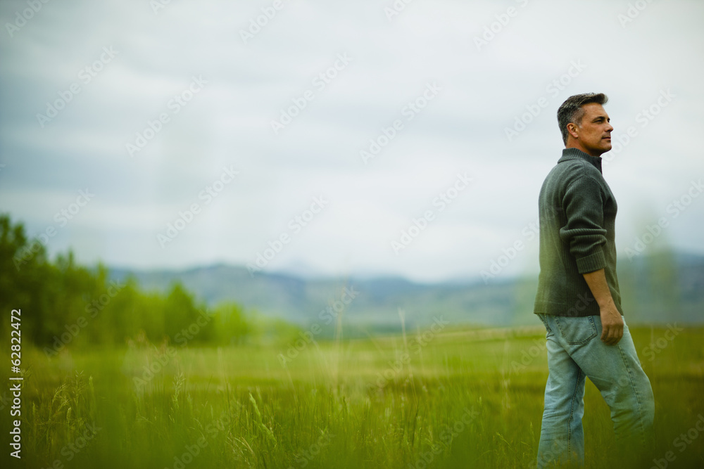 A man standing alone looking into the distance, deep in thought. A man standing alone looking into the distance, deep in thought.