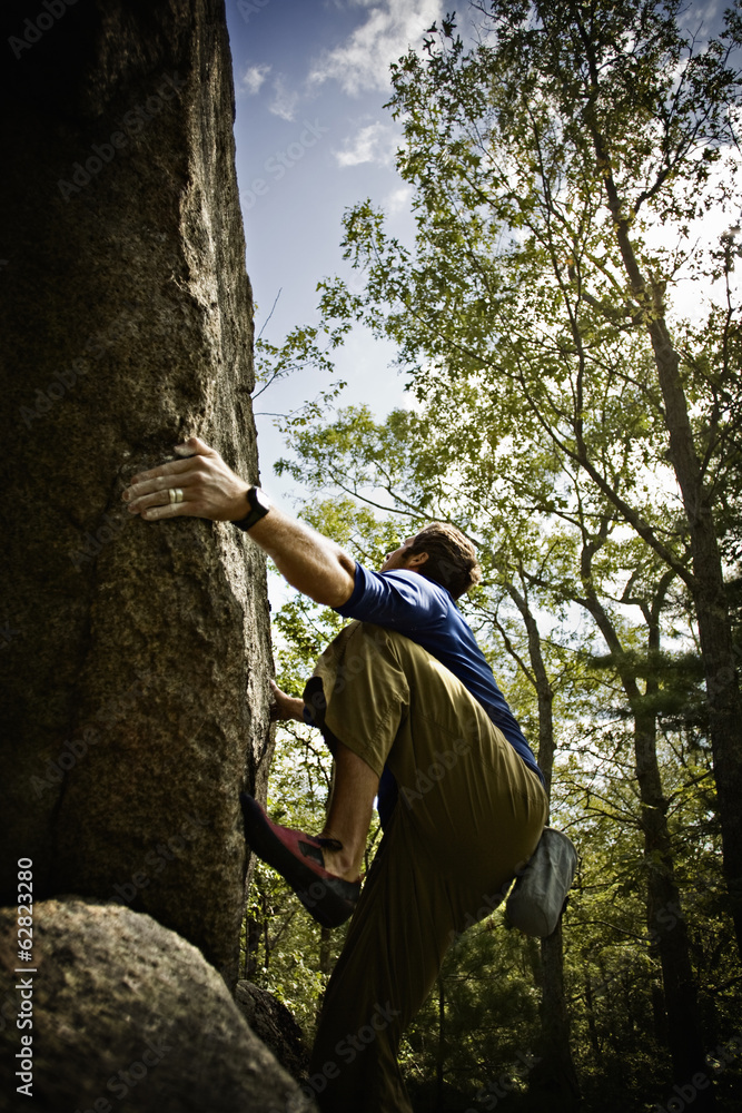 Bouldering, a climber climbing steep cliffs in the woods near Essex