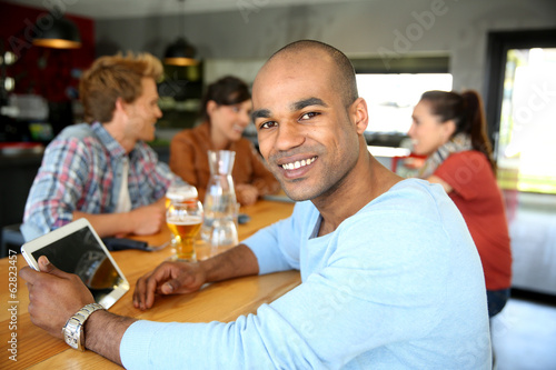 Young man sitting at lounge table with tablet