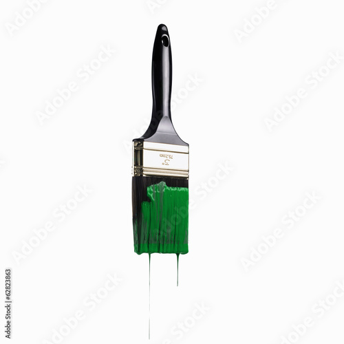 A paintbrush loaded with green paint dripping off the bristles. 