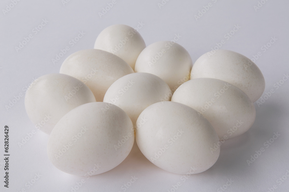 A small group or clutch of nine free range organic egg with white shells against a white background. A small group or clutch of nine free range organic egg with white shells against a white background.
