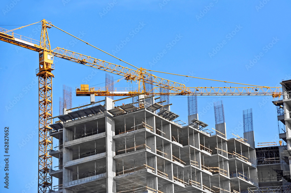 Crane and building construction site against blue sky