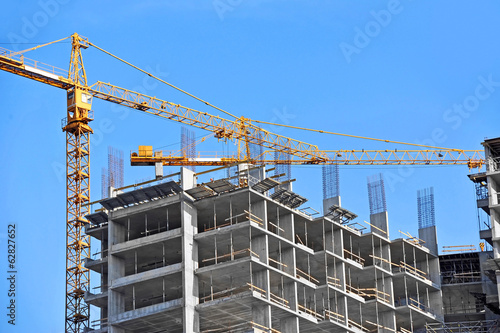 Crane and building construction site against blue sky