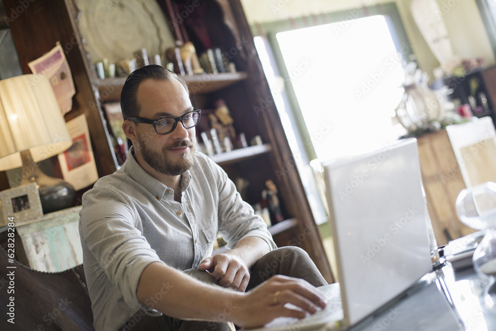 A man sitting at a desk using a laptop computer. Running a small business. A man sitting at a desk using a laptop computer. Running a small business.