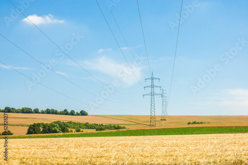 High voltage towers in agricultural fields. © unruhelena