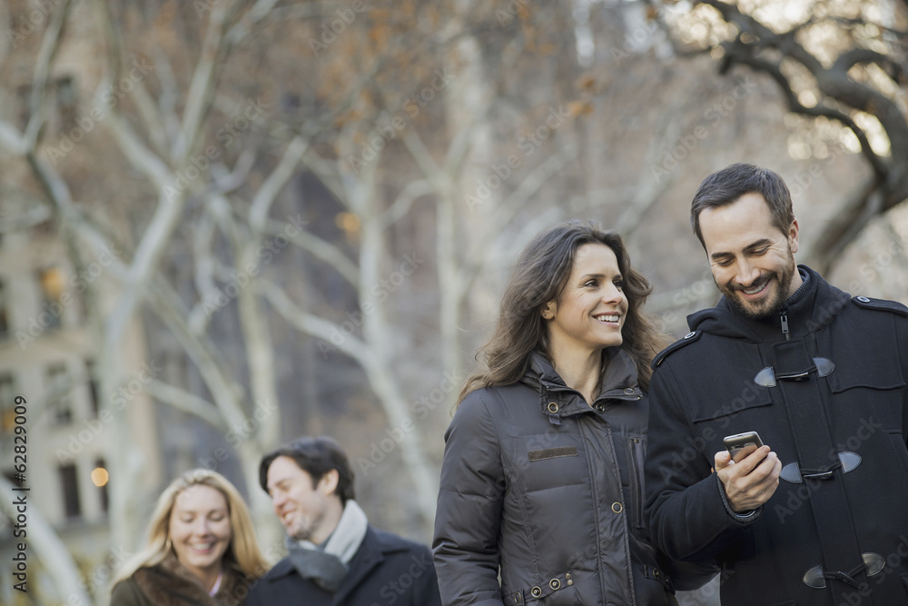 Couple walking in urban park with smartphone Couple walking in urban park with smartphone