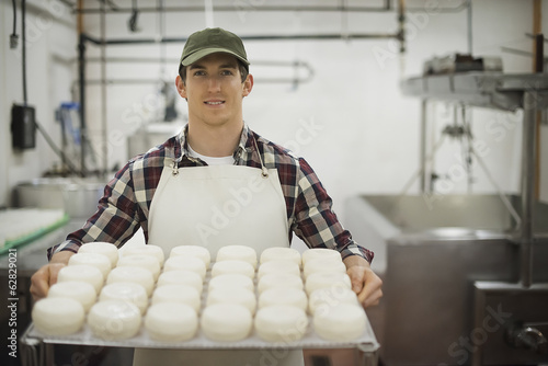 A small organic dairy farm with a mixed herd of cows and goats. Dairy building with large wheels of cheese maturing. Trays of produce.