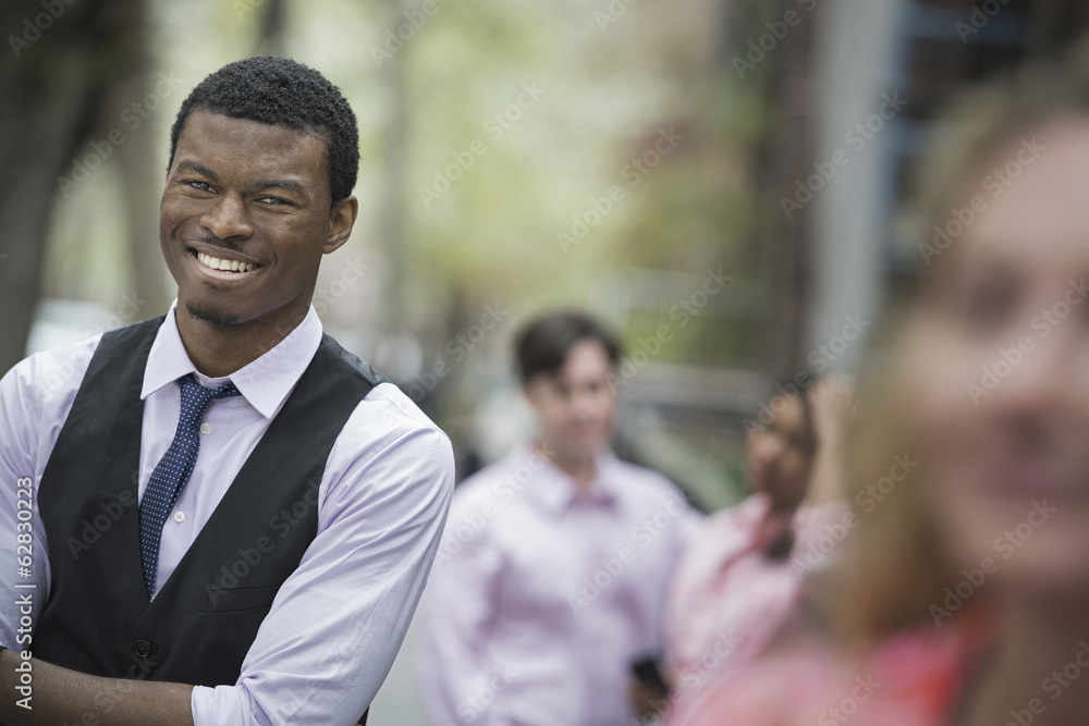 City life in spring. Young people outdoors in a city park. A man with arms folded smiling, and three other people grouped around him. City life in spring. Young people outdoors in a city park. A man with arms folded smiling, and three other people grouped around him.
