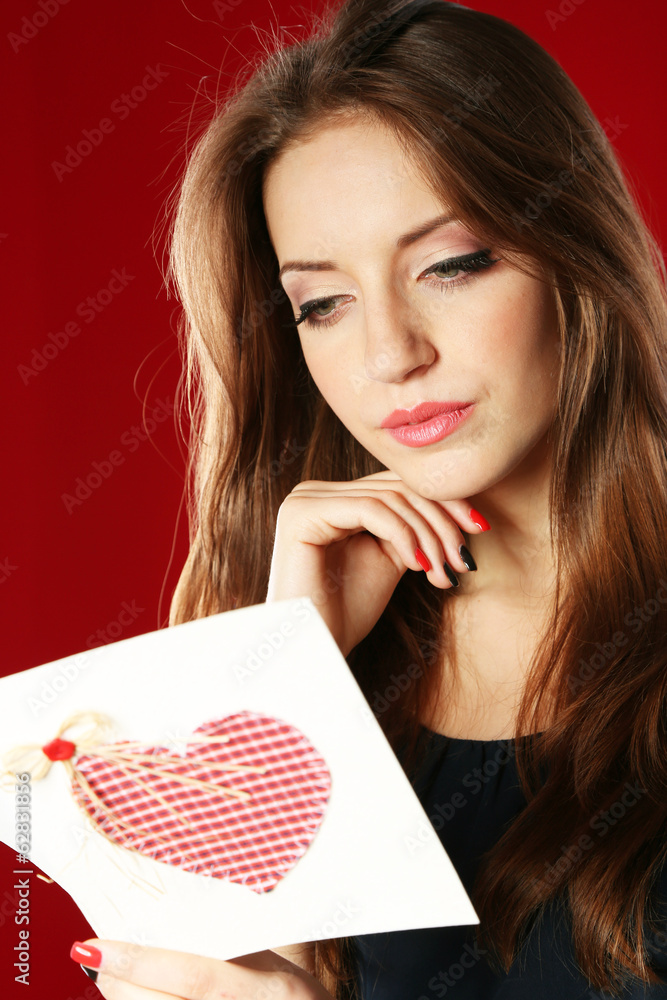 Attractive woman with postcard, on red background Attractive woman with postcard, on red background