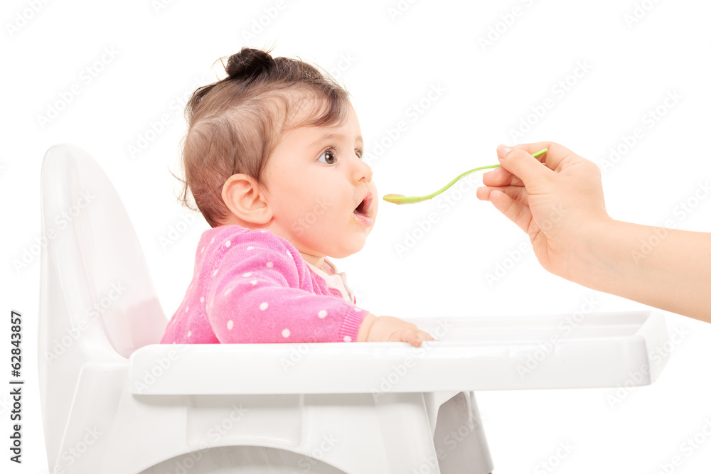 Baby girl being fed in a feeding chair Baby girl being fed in a feeding chair