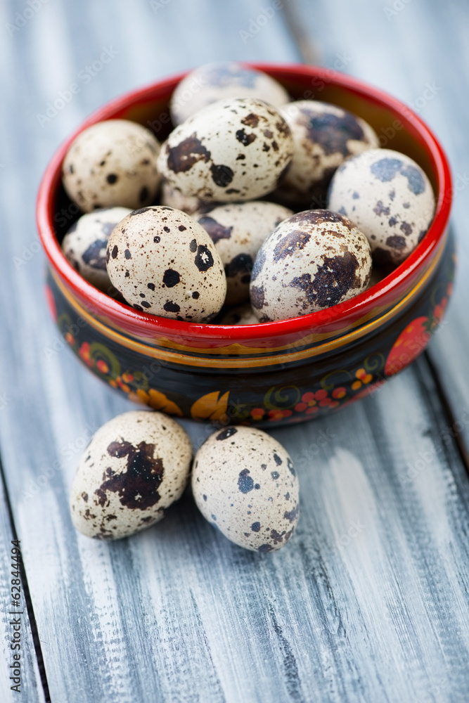 Raw quail eggs in a wooden khokhloma bowl, studio shot Raw quail eggs in a wooden khokhloma bowl, studio shot
