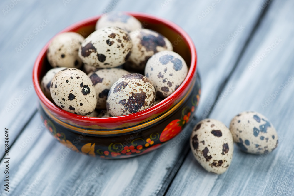 Wooden khokhloma bowl with raw quail eggs, horizontal shot Wooden khokhloma bowl with raw quail eggs, horizontal shot