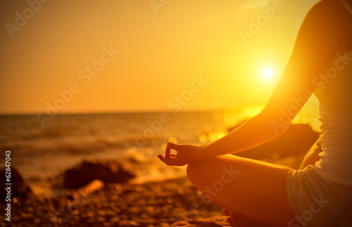 Photo hand of  woman meditating in a yoga pose on beach at sunset