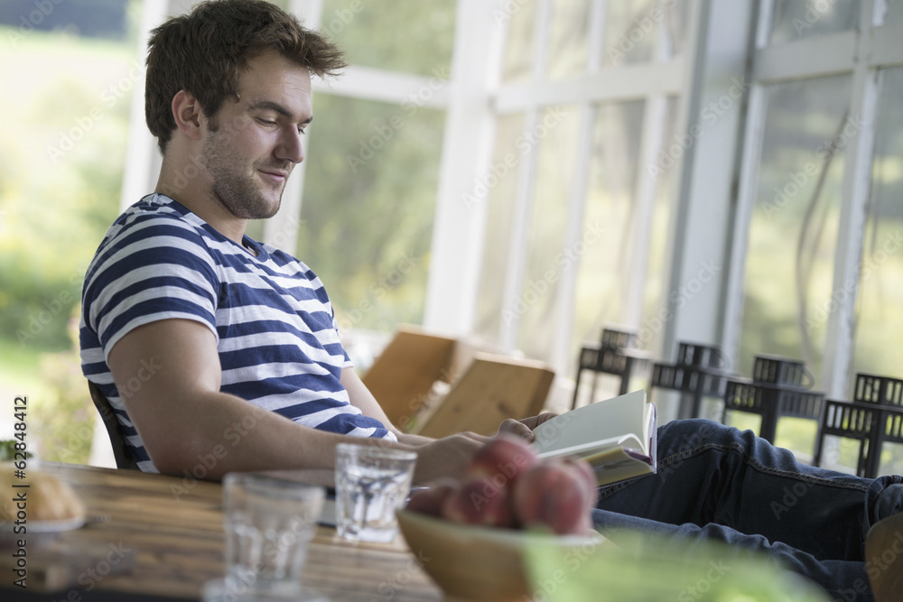 A man sitting at a table reading a book. A man sitting at a table reading a book.