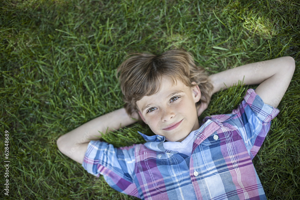 A boy lying on the grass, hands behind his head. A boy lying on the grass, hands behind his head.