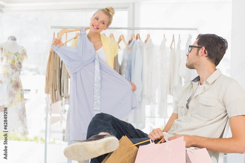 Fototapeta premium Man with shopping bags while woman selecting a dress