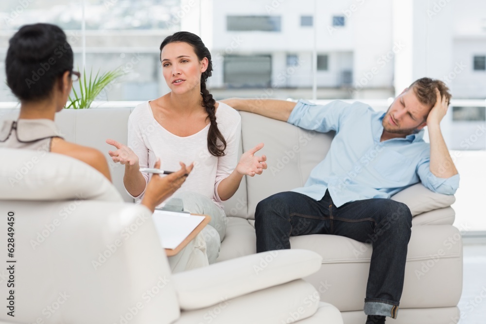 Fototapeta premium Angry couple sitting on couch talking to therapist