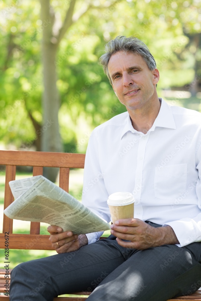 Businessman with disposable cup and newspaper in park Businessman with disposable cup and newspaper in park