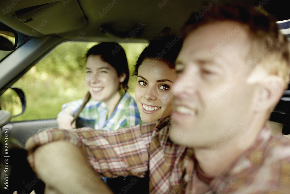 Three passengers in the cab of a pickup truck. One young man driving. Two young women sitting beside him. Three passengers in the cab of a pickup truck. One young man driving. Two young women sitting beside him.