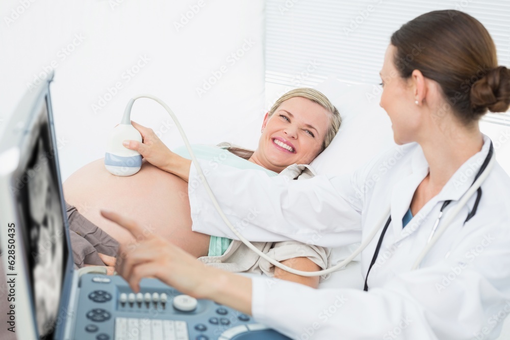 Happy female doctor showing woman her baby on ultrasound Happy female doctor showing woman her baby on ultrasound