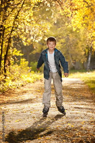 Boy on the roller on the autumn alley