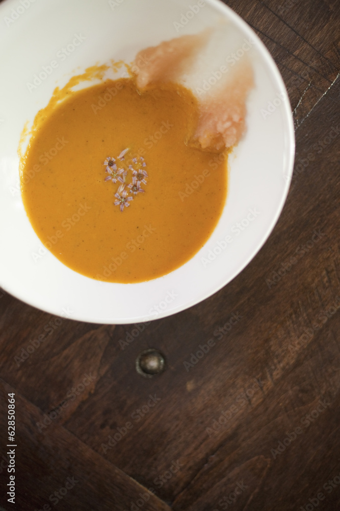 A white china bowl with a creamy soup and garnish, viewed from above. A rouille puree on the side of the dish. A white china bowl with a creamy soup and garnish, viewed from above. A rouille puree on the side of the dish.