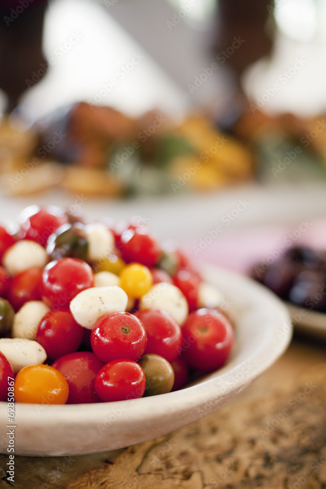 Organic prepared vegetables on a dish, laid out for a party. Heirloom red and orange tomatoes and bocancini salad. A farm stand food stall. Organic prepared vegetables on a dish, laid out for a party. Heirloom red and orange tomatoes and bocancini salad. A farm stand food stall.