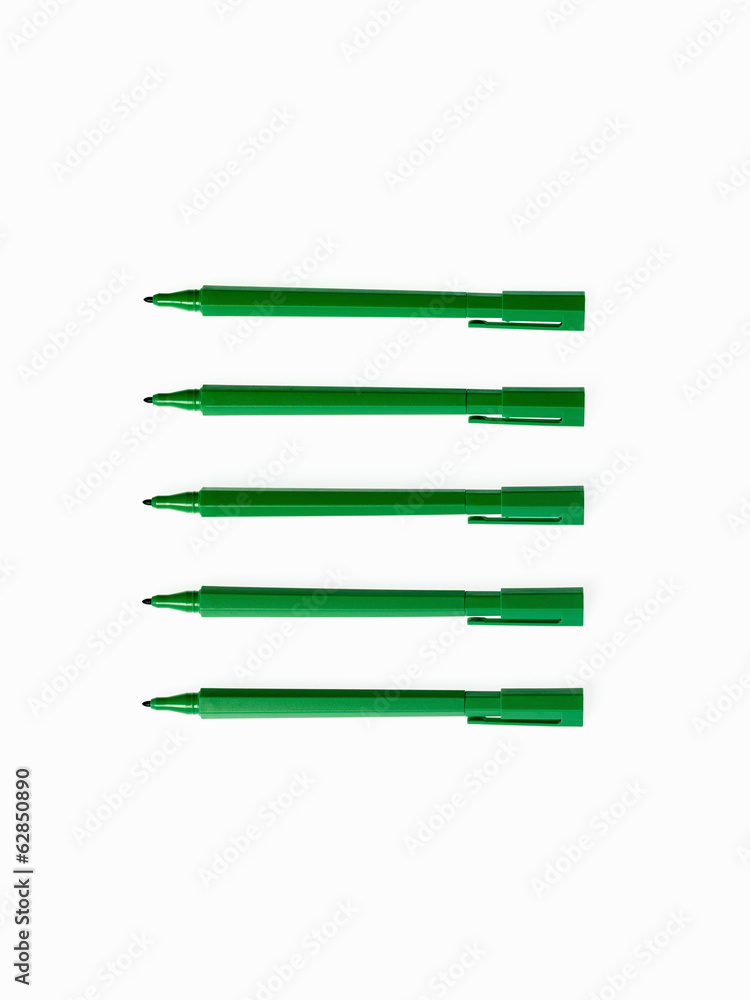 Office supplies. Green coloured pens, felt nibs and pen top cases, arranged in a row. Office supplies. Green coloured pens, felt nibs and pen top cases, arranged in a row.