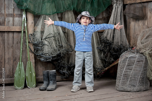 Boy - fishermen in a barn with fishing tackles photo