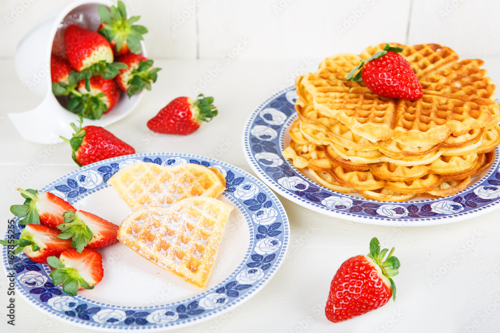 Crisp golden fresh baked waffle topped with strawberries on whit Crisp golden fresh baked waffle topped with strawberries on whit