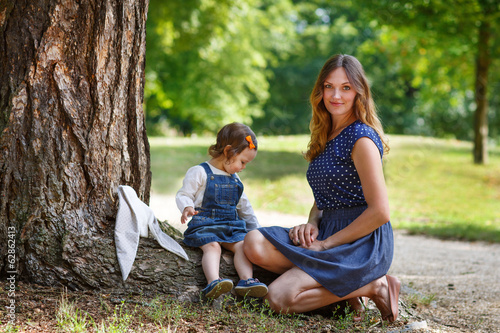 Beautiful mother and little daughter walking in summer park © Irina Schmidt