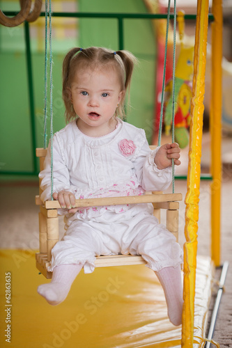 Girl with Down syndrome is riding on a swing