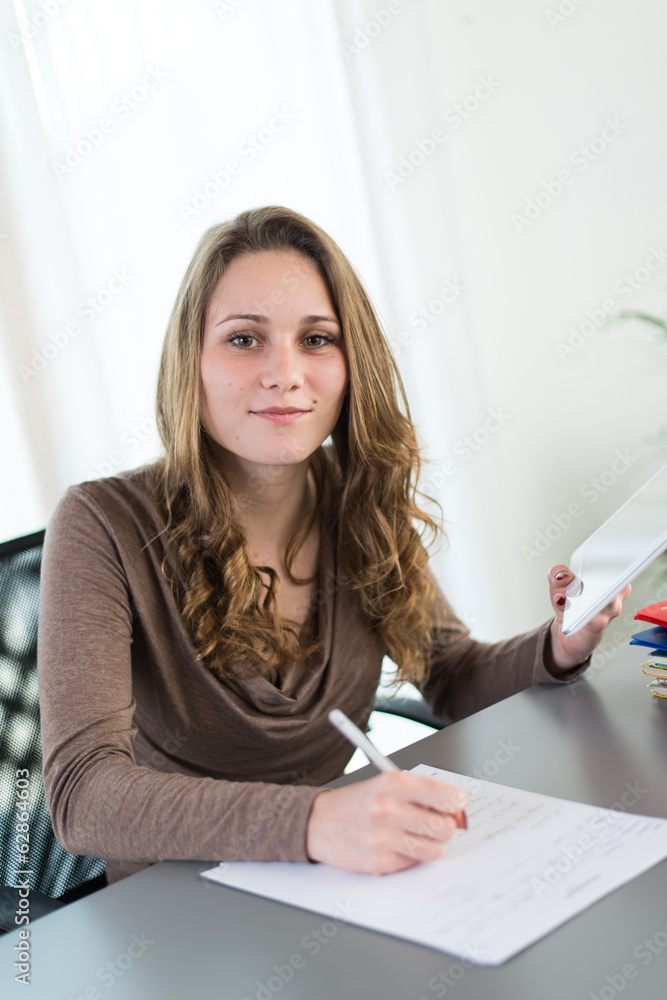 young female student doing homework with computer and cell phone young female student doing homework with computer and cell phone