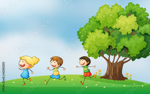 Three energetic kids playing at the hilltop with a big tree