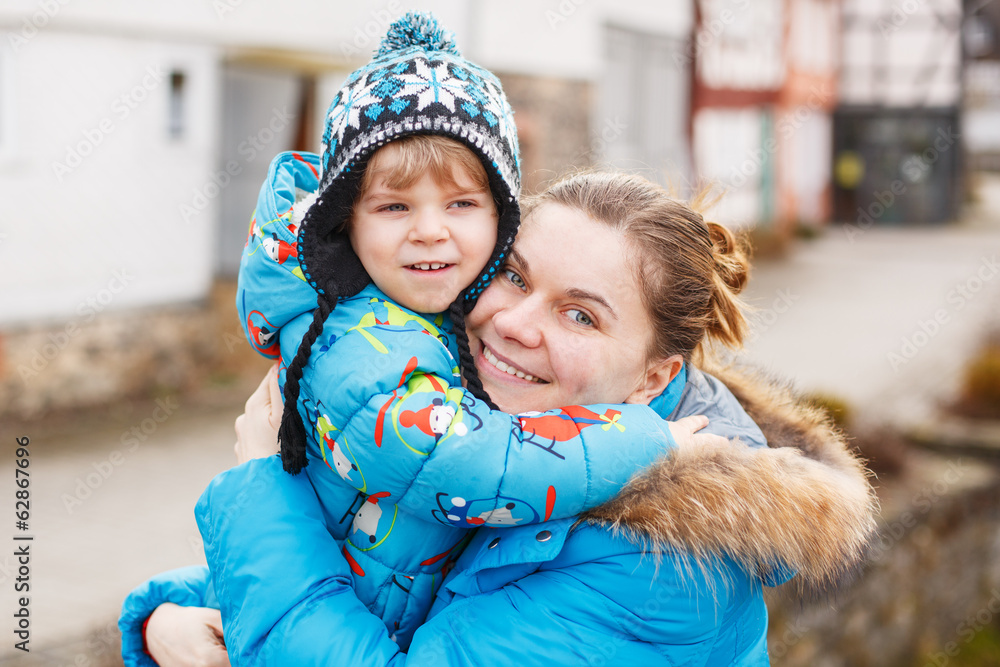 Obraz premium Adorable caucasian little boy and mother hugging on bridge, outd