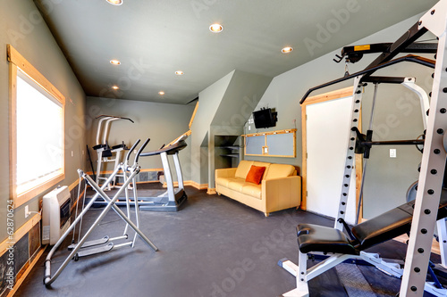 Home gym with yellow couch and TV