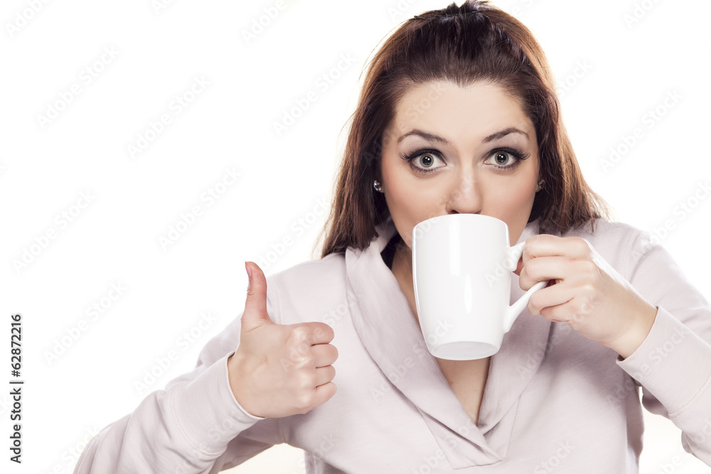 beautiful woman drinking from a cup and showing thumbs up beautiful woman drinking from a cup and showing thumbs up