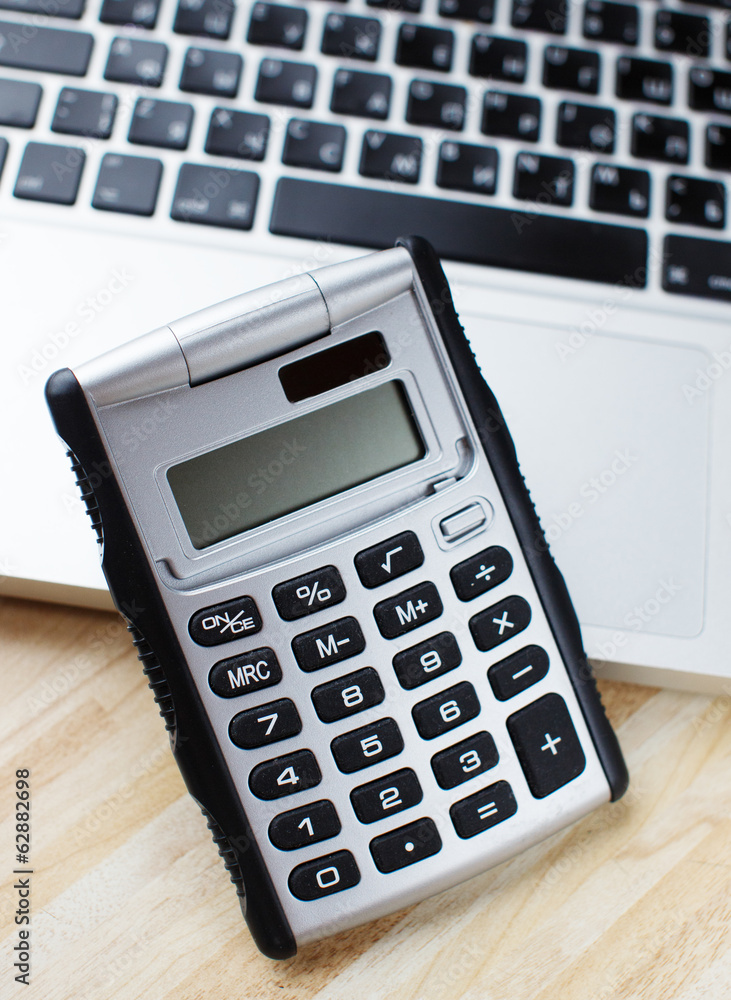 Calculator and a makbook on the background Calculator and a makbook on the background