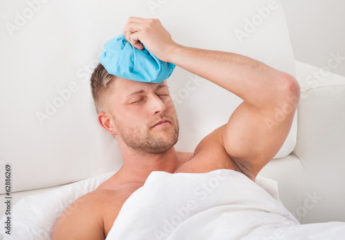 Man nursing a hangover holding an ice pack photo