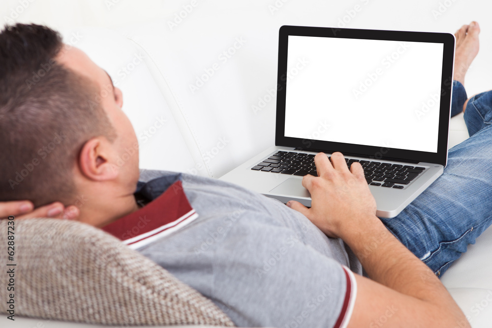 Man Using Laptop While Lying On Sofa Man Using Laptop While Lying On Sofa