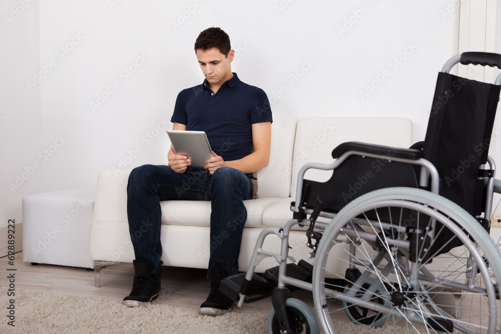 Handicapped Man Using Digital Tablet On Sofa Handicapped Man Using Digital Tablet On Sofa