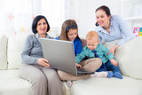 Grandmother, mother, daughter and son using laptop at home.